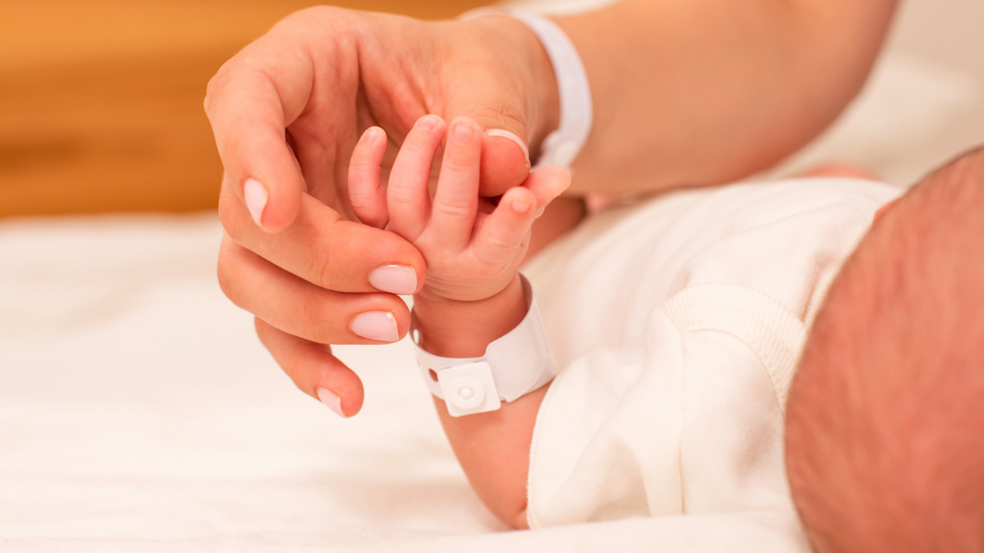 A close-up of a baby's hand clasping adult hand