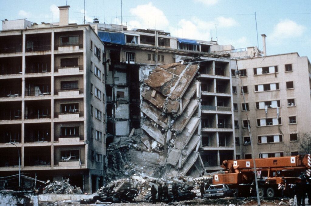 A multi-story city building with a large pile of rubble; devastating scene