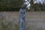 stone statue of a woman in a walled garden